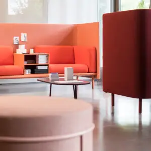 Moderner Wartebereich mit orange-roten Sofas, Tisch, Broschüren und glänzendem Boden.